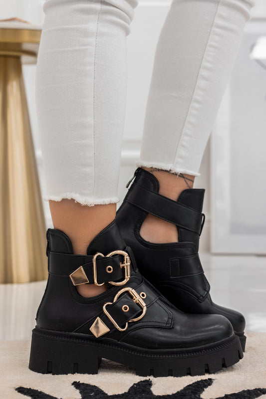 FILE - Open black ankle boots with gold buckles