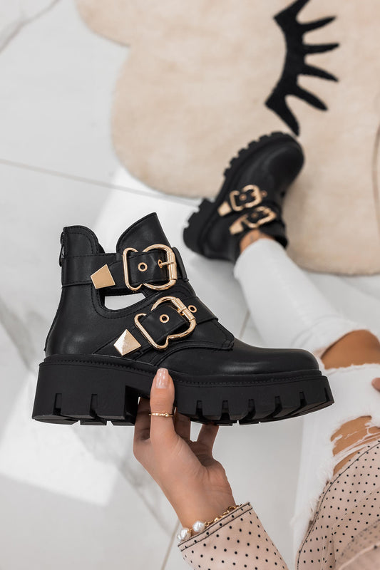 FILE - Open black ankle boots with gold buckles
